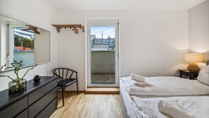 A bedroom with a bed, a desk, a chair, a dresser, and a sliding door leading to a balcony. - Botanical Design Apart in Erlachplatz (Vienna)