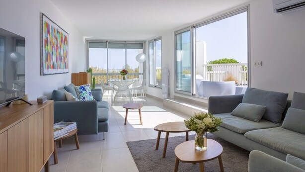 Un salon moderne avec un canapé, une table basse et un balcon offrant une vue agréable.