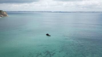 Vista costera con un barco en el agua y un acantilado a la izquierda.