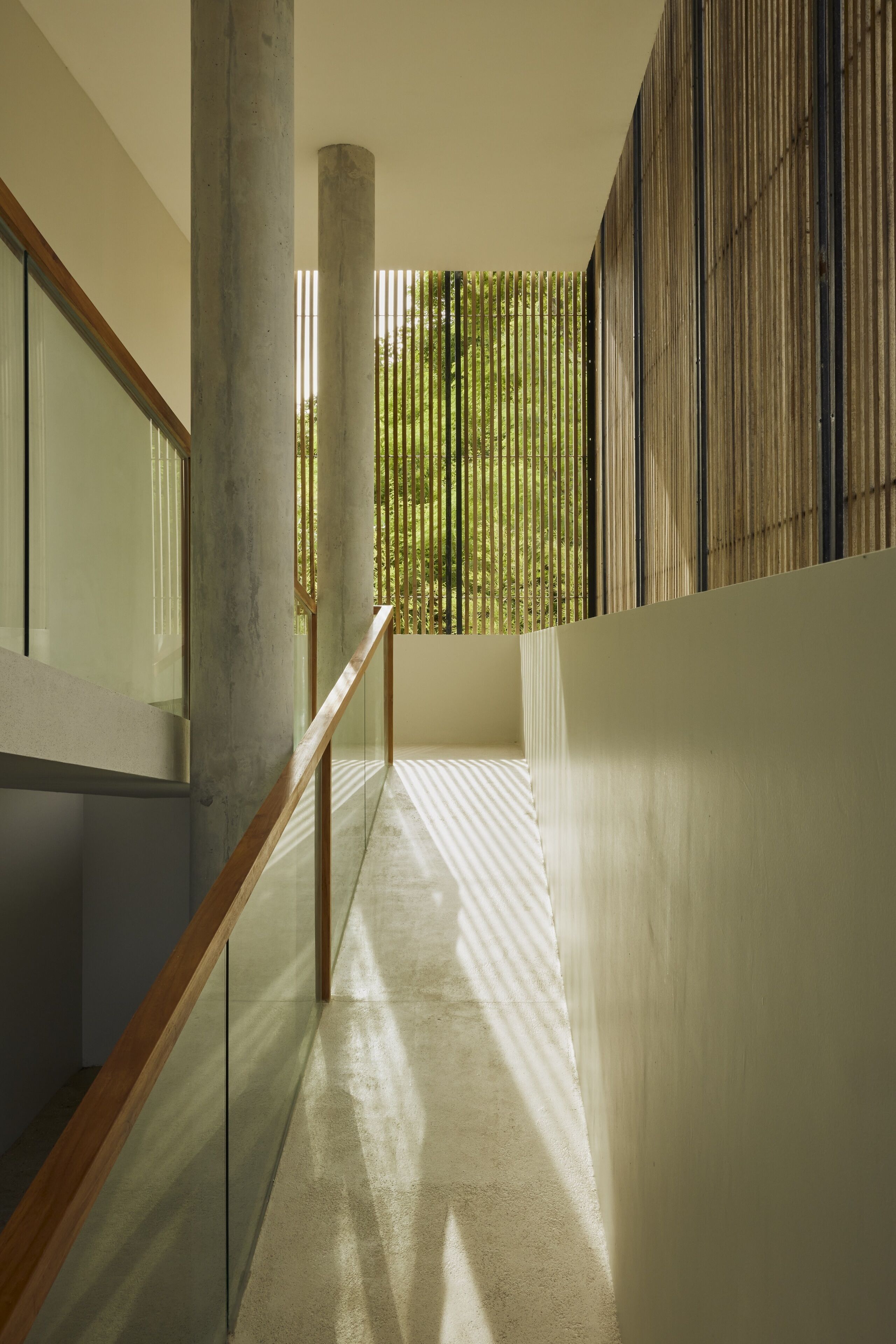 A modern interior with a concrete column, a wooden railing, and a bamboo screen.