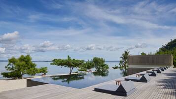 Una piscina al aire libre, sillones reclinables de piscina