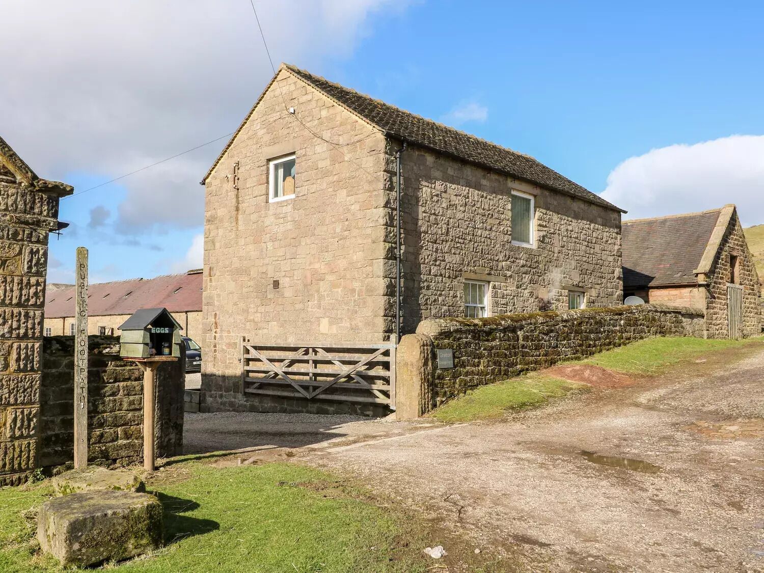 A stone building with a traditional design, a wooden gate, and a gravel driveway.