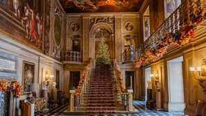 Una imponente escalera con decoraciones elaboradas, un suelo a cuadros y elementos arquitectónicos clásicos.
