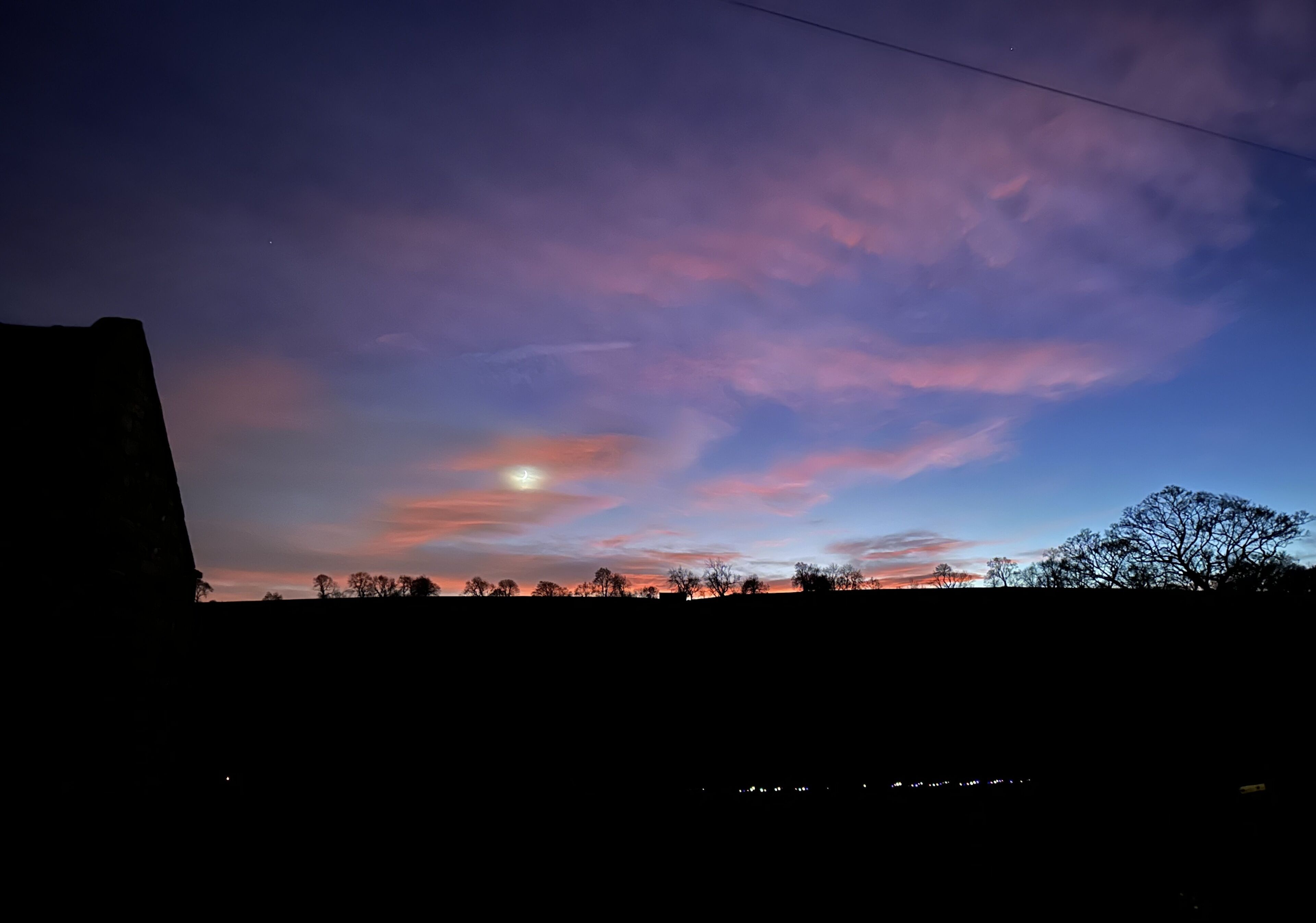 A twilight sky with clouds and a visible moon.