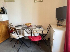 A compact dining area with a table set for two, a microwave, and a television. - Quiet studio, sleeps 4, Risoul 1850, near center, ski locker (Risoul)