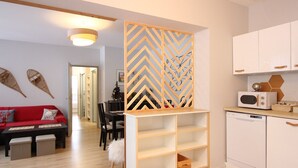 Una cocina moderna con armarios blancos, un microondas y un mueble de madera con estantes.