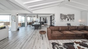 A spacious living area with a modern design, featuring a brown leather sofa, a wooden coffee table, and a cowhide rug. - Sandbanks Villa (Yzerfontein)