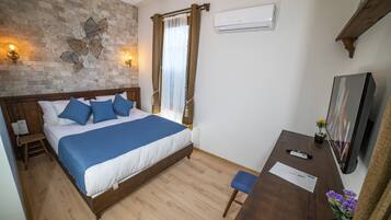 A bedroom with a wooden bed, a desk, a chair, a TV, and a wall-mounted air conditioner.