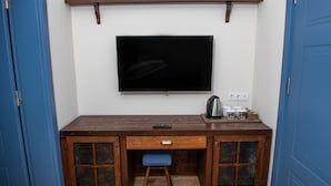 Ein kleiner Raum mit einem Holztisch, einem an der Wand befestigten Fernseher und einer blauen Tür.