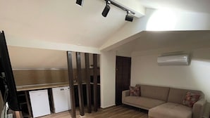 Ein modernes Wohnzimmer mit einer Couch und einer Küchenzeile im Hintergrund.