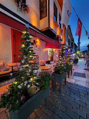 Un espace extérieur accueillant, aménagé avec des sapins de Noël et des tables, un restaurant appelé « Crescent d’Or » doté d’un auvent rouge, et un drapeau orné d’un croissant de lune et d’une étoile.