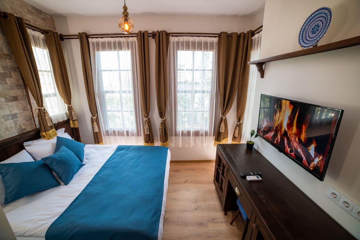 A bedroom with a bed, a TV, and a desk.