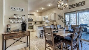 A spacious kitchen with a central island, white cabinetry, and a coffee station.