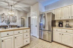 A modern kitchen with white cabinetry, a stainless steel refrigerator, and a built-in coffee maker.