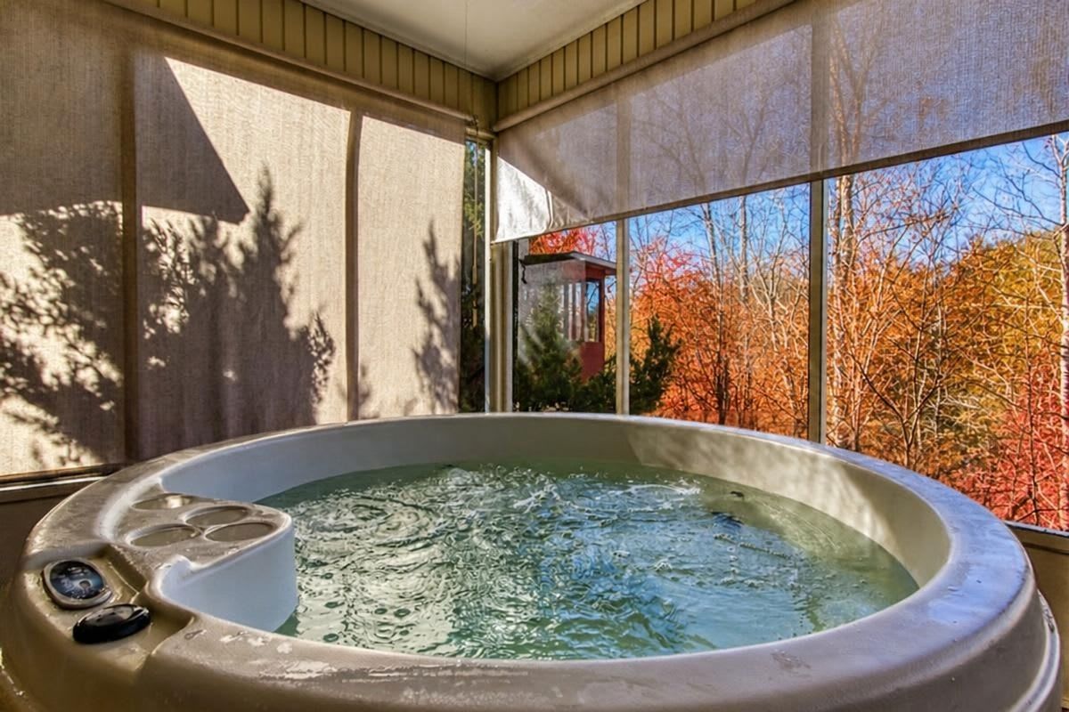 Un bain à remous avec vue sur les arbres aux couleurs automnales, visible à travers une fenêtre.