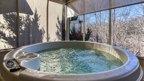 A hot tub with a view of trees through large windows.