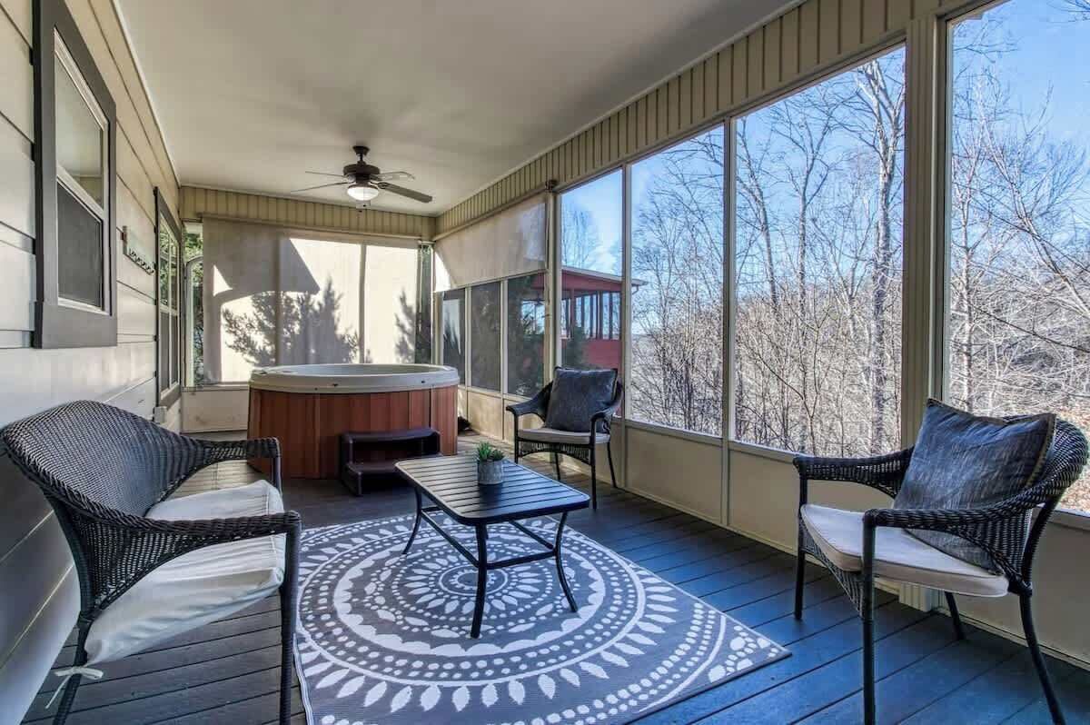 En overdækket veranda med fletmøbler, jacuzzi og ventilator.