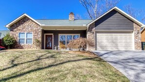 A single-story house with a stone facade, a front garage, and a well-maintained lawn.