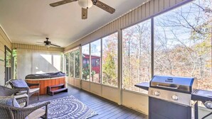 A covered outdoor area with a hot tub, seating, and a grill.