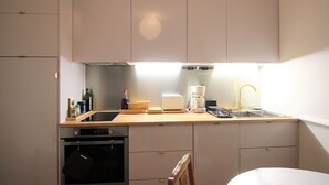 A compact kitchen with a built-in oven, a coffee maker, and a sink. - Mont-Dore Center: Beautiful T2 Apartment with Wifi Near the Thermal Baths (Mont-Dore)