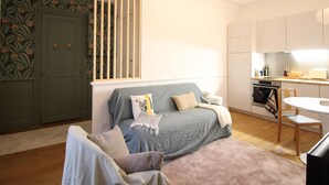 A compact living space with a sofa bed, a dining table, and a kitchen area. - Mont-Dore Center: Beautiful T2 Apartment with Wifi Near the Thermal Baths (Mont-Dore)