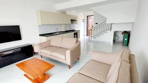 A modern living room with a flat-screen TV, beige sofas, and a wooden coffee table.