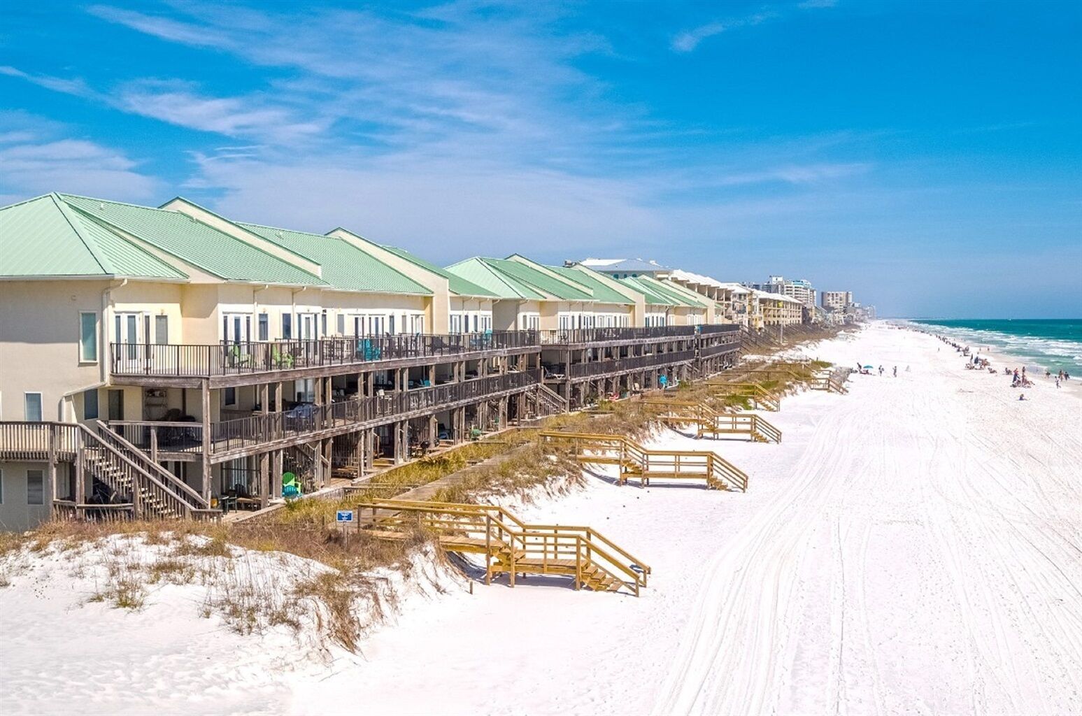 A beachfront hotel with multiple balconies, a sandy beach, and ocean views.