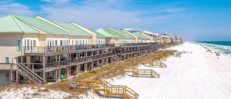 A beachfront hotel with multiple balconies, a sandy beach, and ocean views.