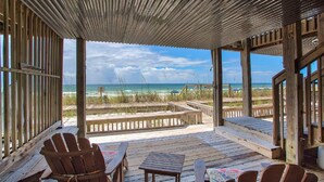 Una terraza de madera con vista a la playa y al océano.