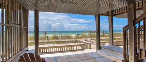 A wooden deck with a view of the beach and ocean.