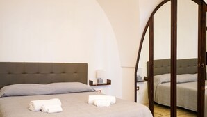 Ein Hotelzimmer mit einem großen Bett, einem Spiegel, einem Nachttisch und einer kleinen Ablagefläche.
