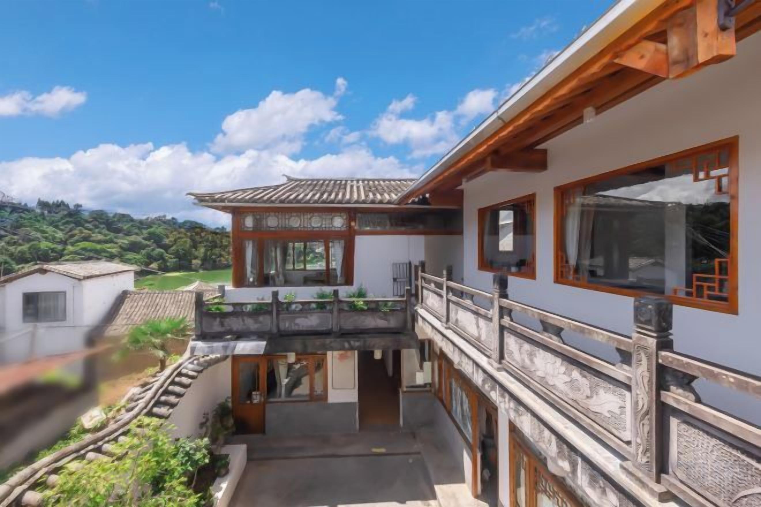 A traditional building with a balcony, a staircase, and a view of a green landscape.