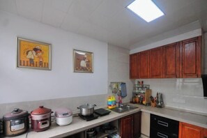 A kitchen with wooden cabinets, a countertop with various appliances, and two framed pictures on the wall.