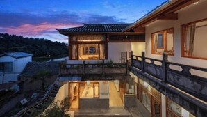 A traditional Japanese house with a wooden balcony and a view of the surrounding landscape.