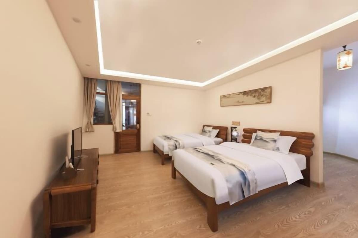 A hotel room with two beds, a desk, and a ceiling light fixture.