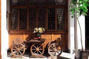 A traditional wooden table with two chairs, a vase with flowers, and a window with intricate lattice design. - Snail Inn (Tengchong) (Tengchong)