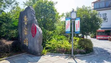 A stone monument with inscriptions, a signboard with text, and a building in the background.