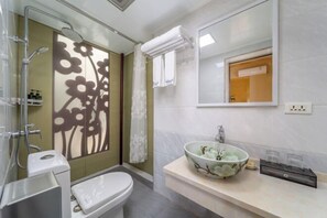 A bathroom with a toilet, a shower, a sink with a floral bowl, and a mirror. - Peach Blossom Bay Resort (Guilin Ludiyan Scenic Area) (Guilin)