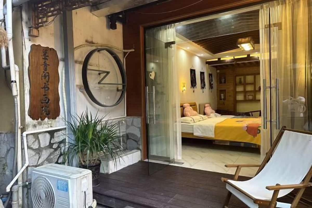Una habitación con una cama, una silla, un reloj y una planta en maceta.