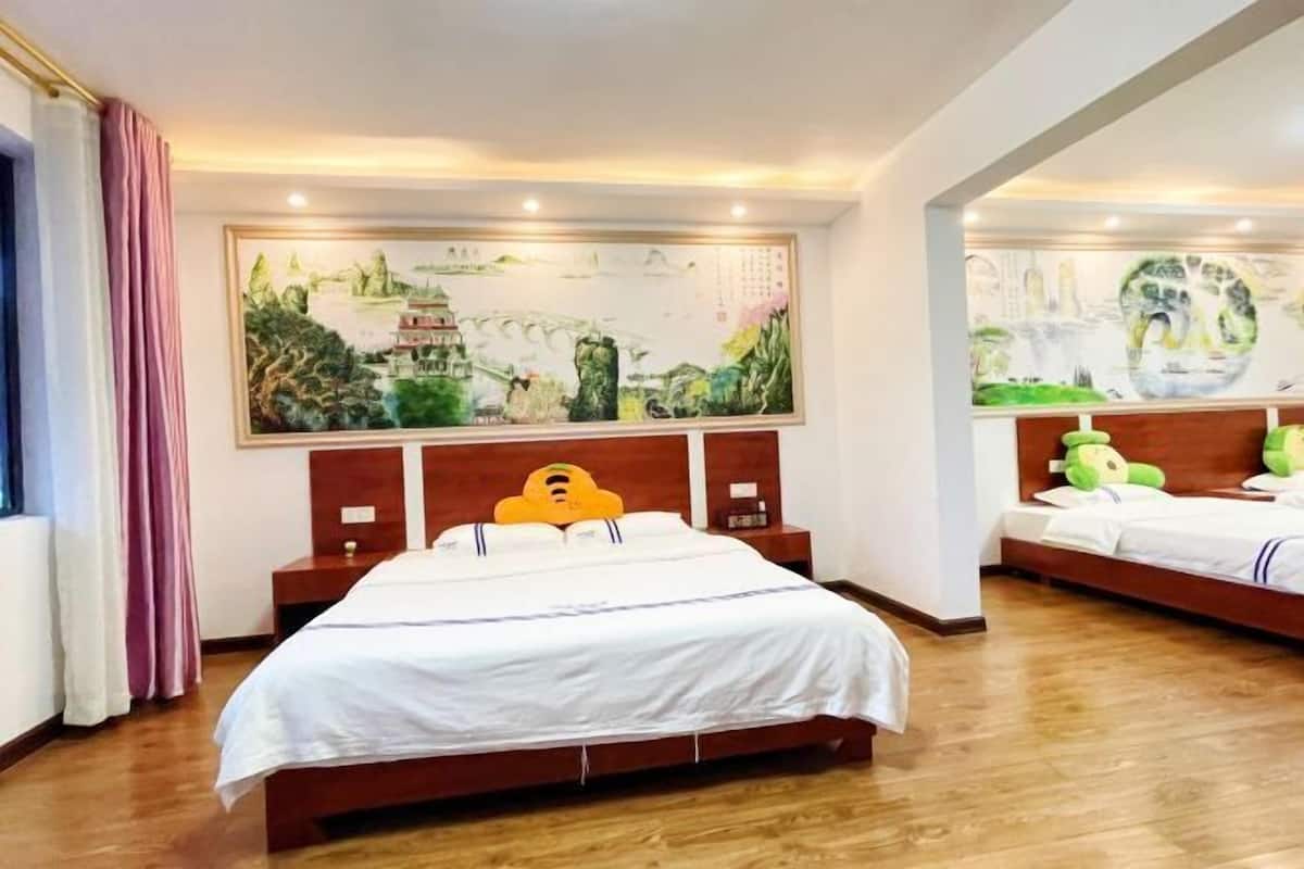 Habitación de hotel con una cama grande, una cama más pequeña, cabeceros de madera y un cuadro grande en la pared.