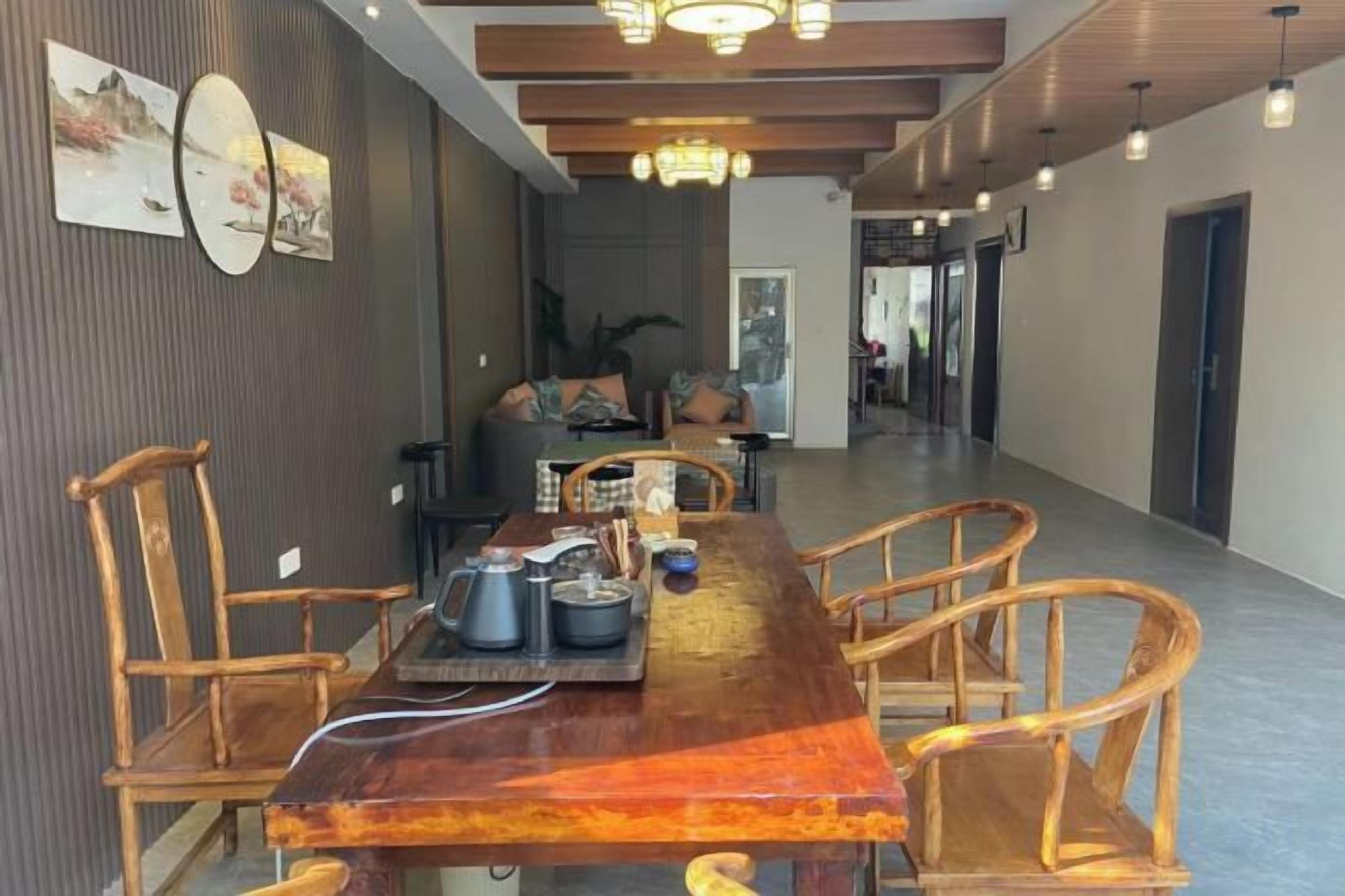 A dining area with a long wooden table, chairs, and a tray with teapots.