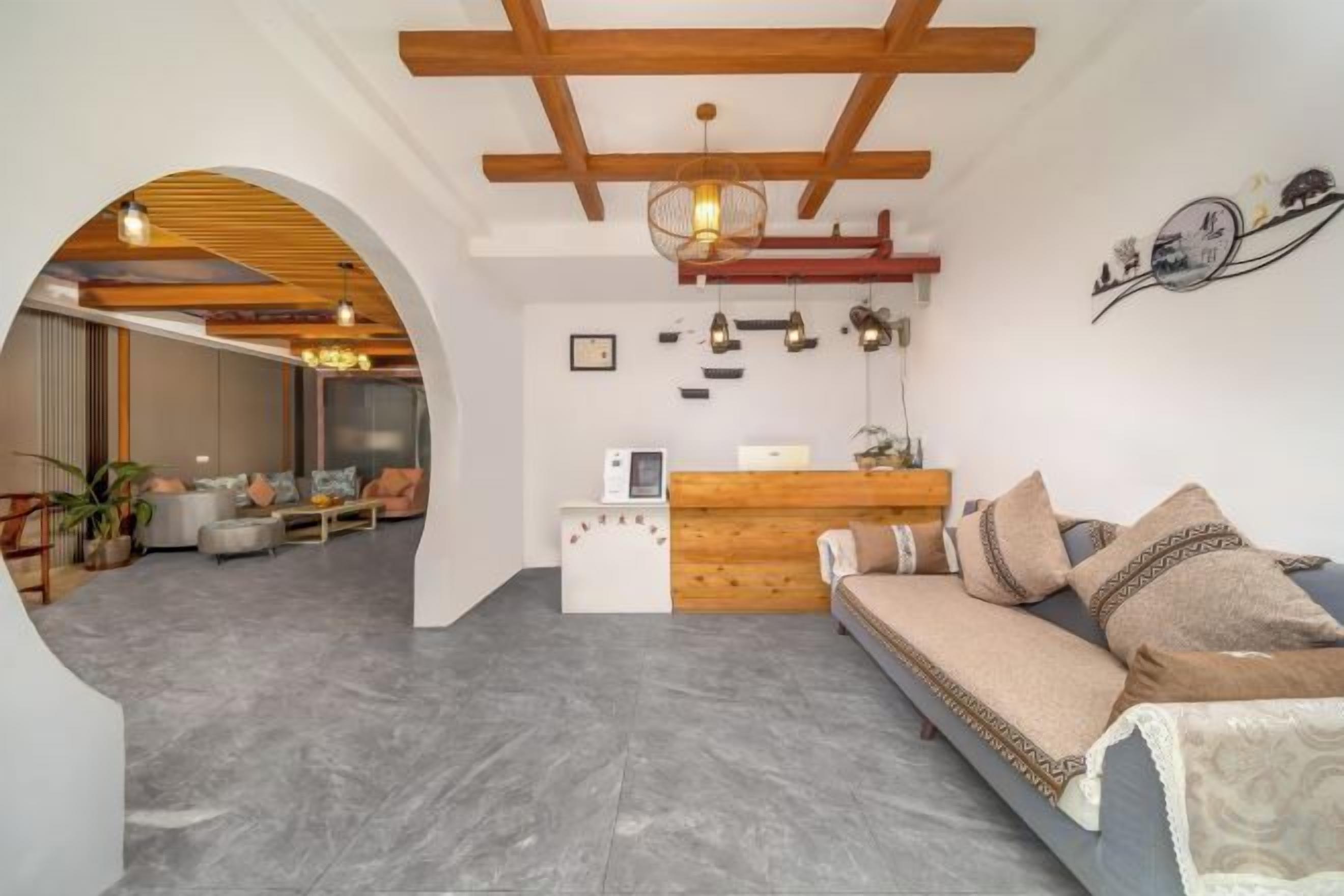 Un interior moderno con una recepción, un sofá con cojines estampados y una estructura de techo de madera.