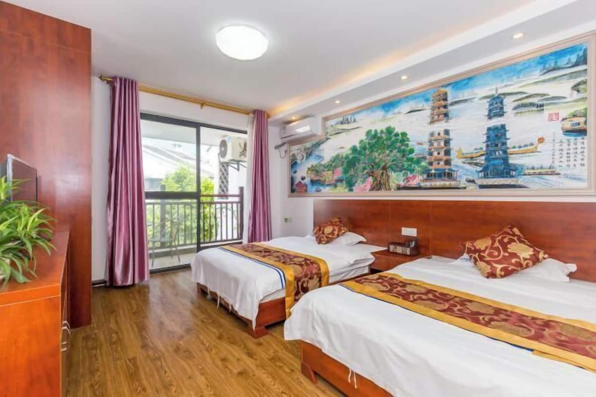 Habitación de hotel con dos camas, un cuadro grande de arquitectura tradicional, un balcón con vistas y suelo de madera.