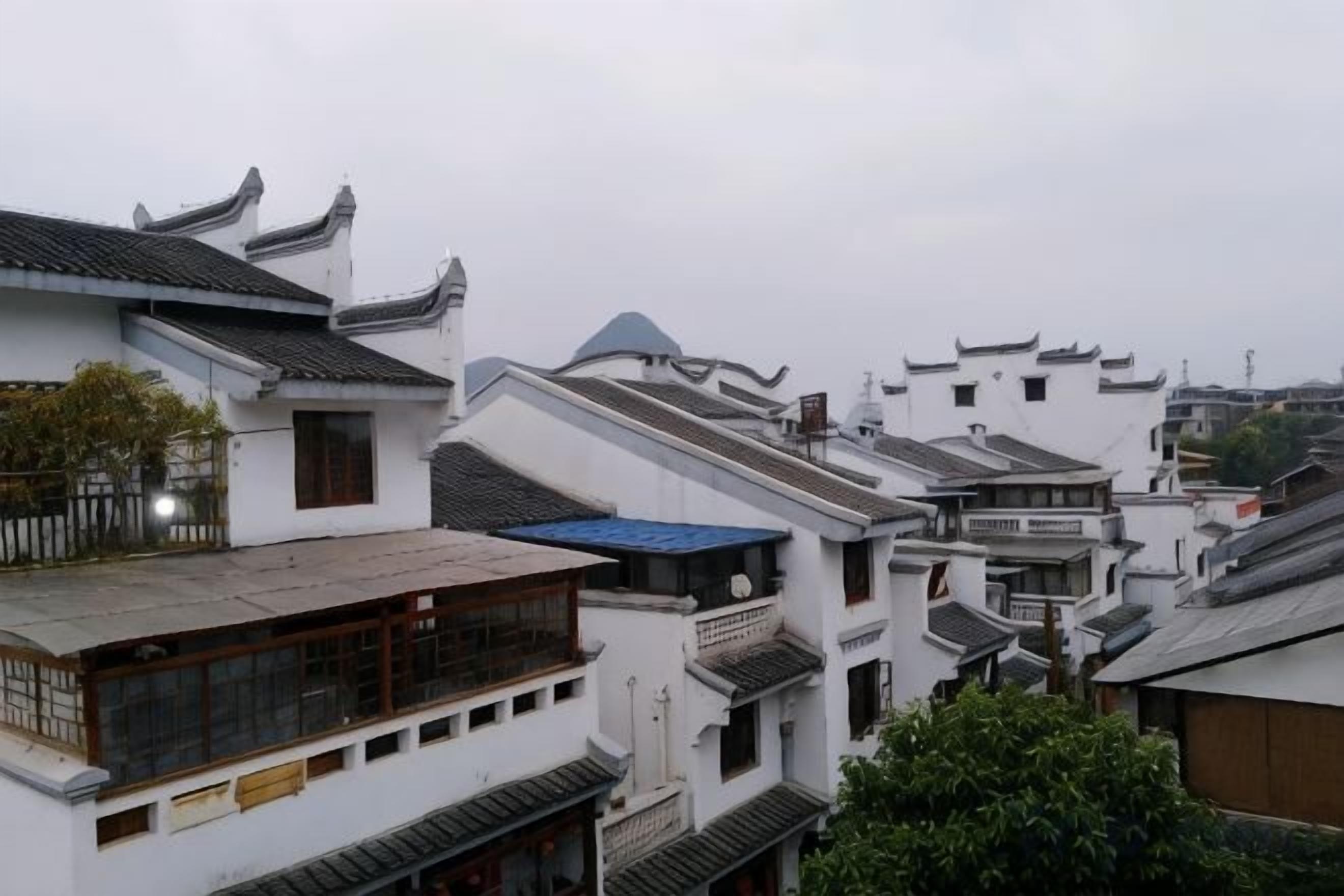 A traditional multi-story building with a sloped roof, wooden balconies, and a mix of white and grey exteriors.
