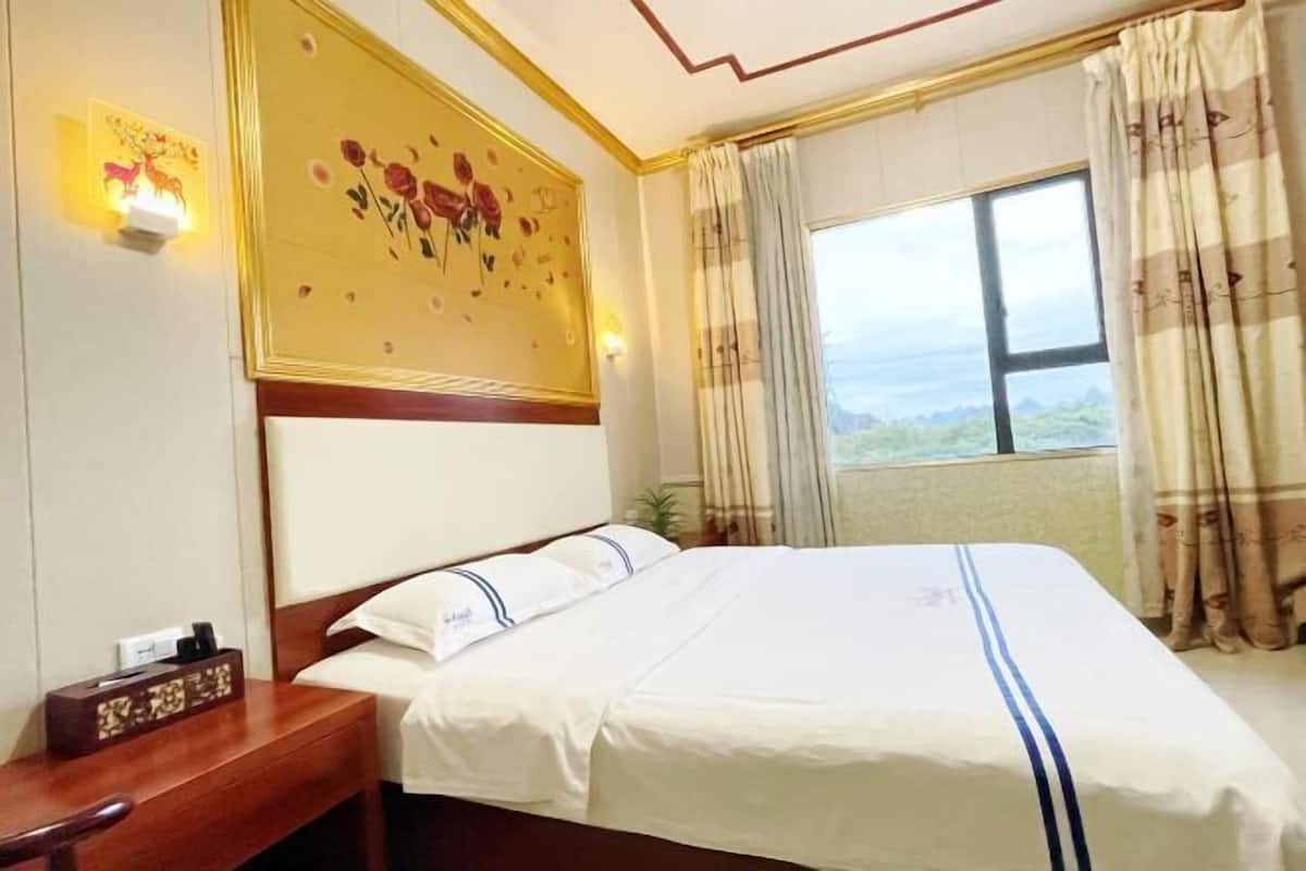 Habitación de hotel con cama, mesita de noche, decoración en la pared y ventana con vistas.