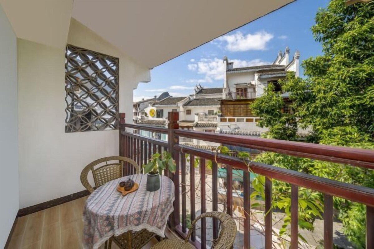 A balcony with a table and chairs, a decorative wall, and a view of traditional buildings.