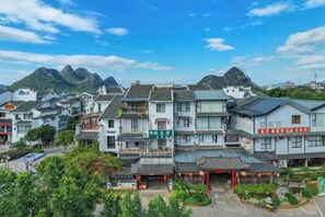 A traditional multi-story building with a courtyard, surrounded by greenery and mountains in the background. - Peach Blossom Bay Resort (Guilin Ludiyan Scenic Area) (Guilin)