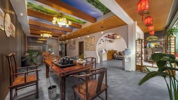A dining area with a wooden table and chairs, a ceiling with a green wall design, and red lanterns.