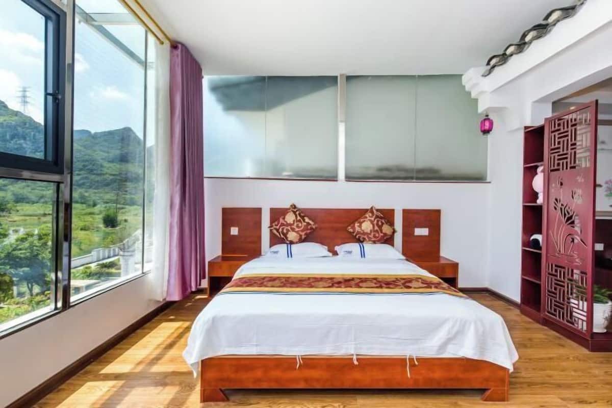 Un dormitorio con un ventanal grande, una cama de madera y un cabecero decorativo.