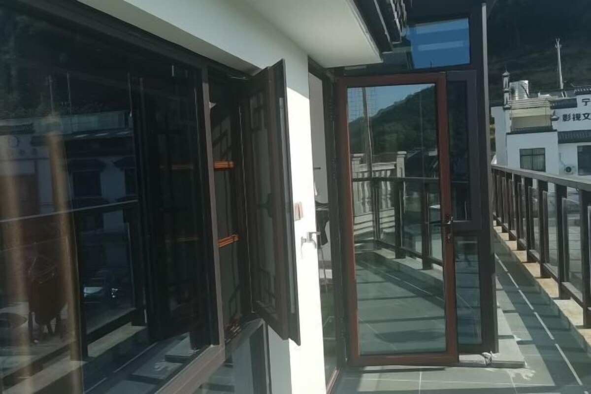 A modern building with large glass windows and a balcony with a metal railing.